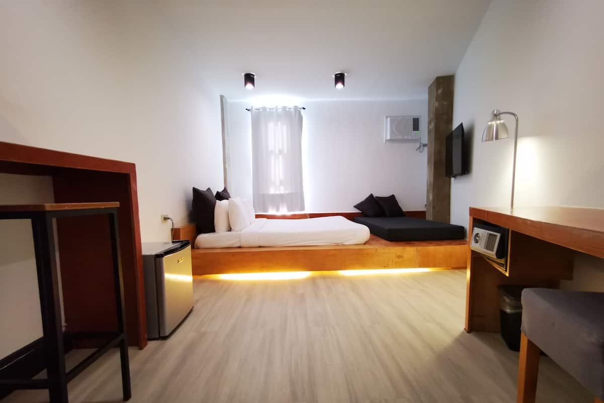 Une chambre d’hôtel moderne équipée d’un lit, d’une table de chevet et d’un espace bureau.