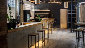 Un espace bar moderne avec un comptoir en bois, des tabourets de bar et une cuisine en arrière-plan.