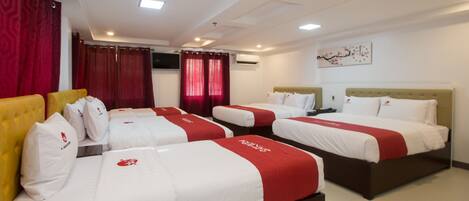 A hotel room with three beds, each with white and red bedding, and a yellow headboard.