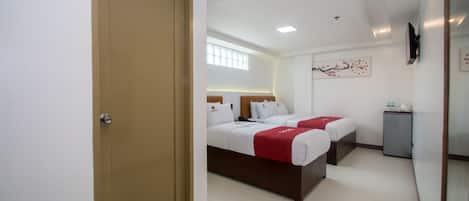 A hotel room with two beds, a small desk, and a mirror.