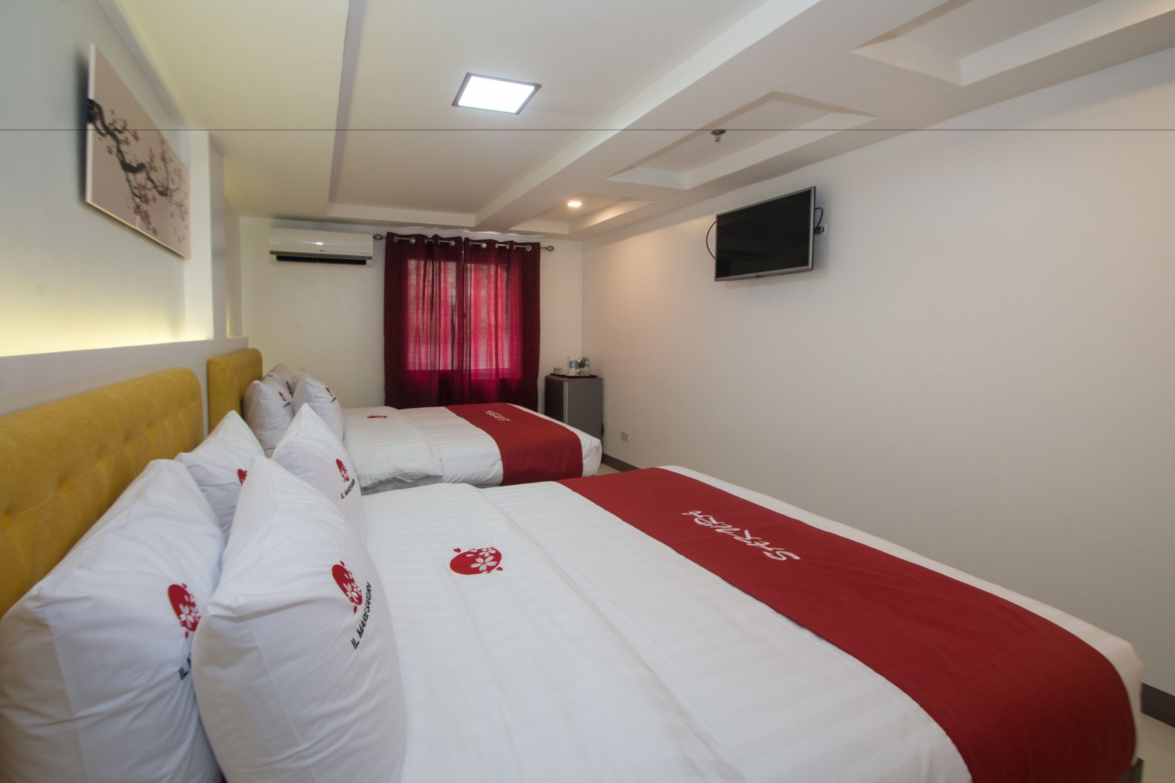 A hotel room with two beds, a flat-screen TV, an air conditioning unit, and a painting on the wall.