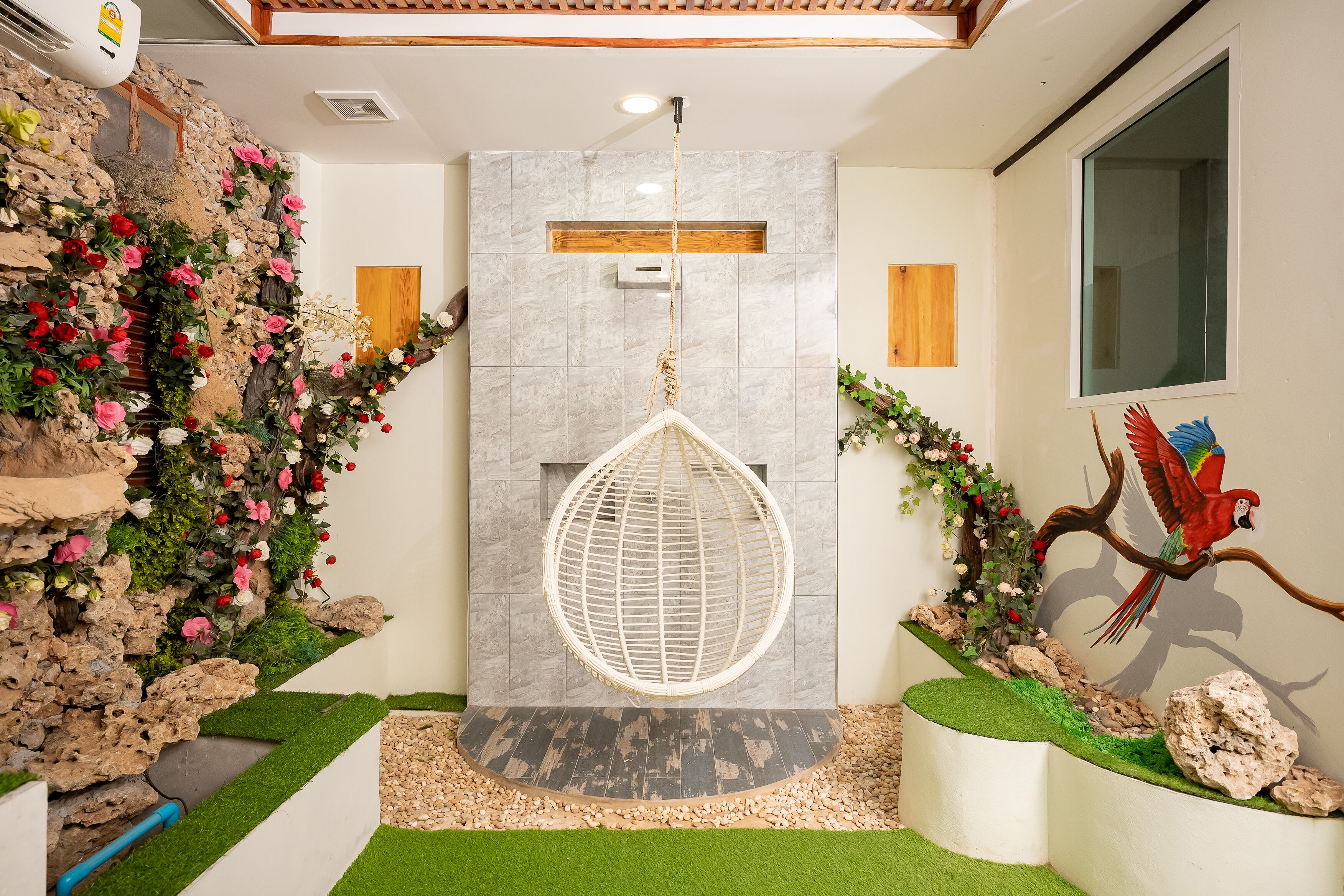 A modern bathroom with a stone wall, a hanging egg chair, and a parrot mural.