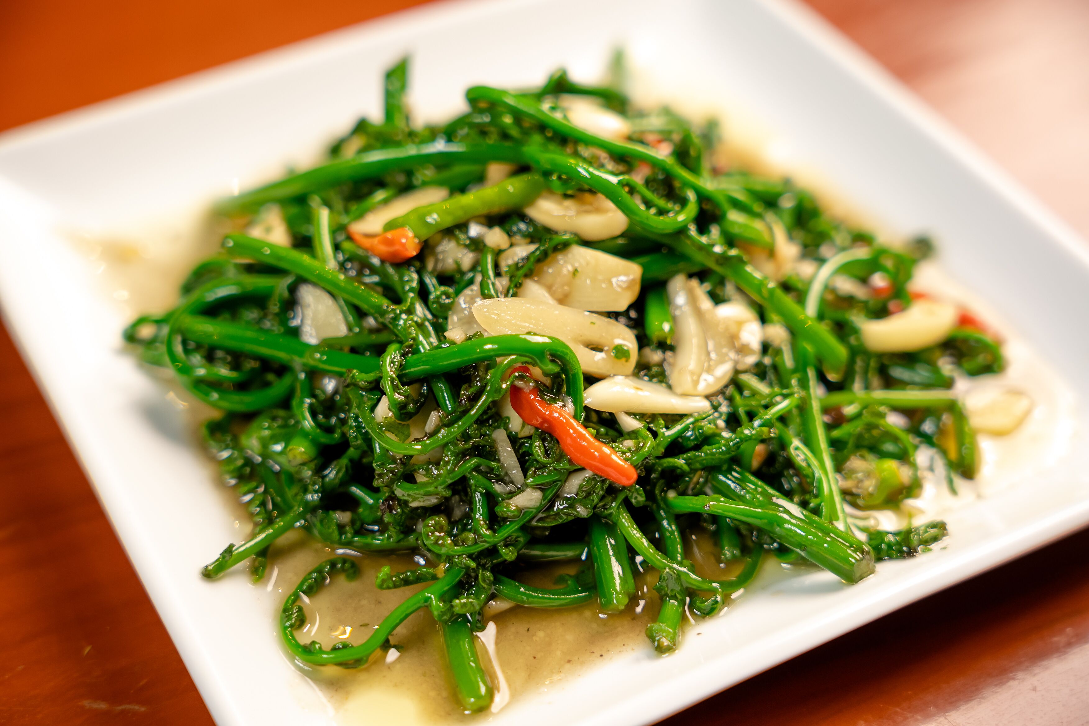 A dish of stir-fried greens with garlic and red chili.