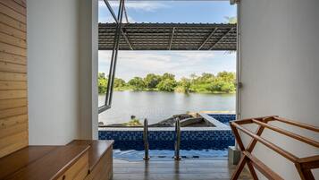 Un banco de madera y una pequeña piscina con vista a un lago y árboles.
