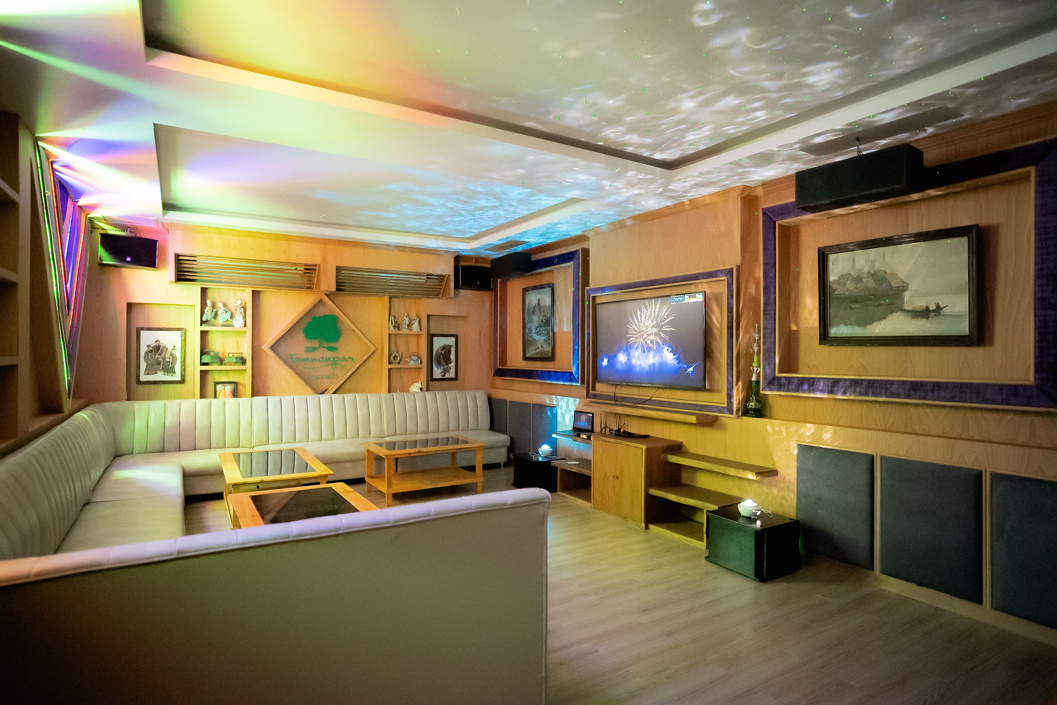 A modern living room with a sectional sofa, a flat-screen TV, and a ceiling with a light projection.