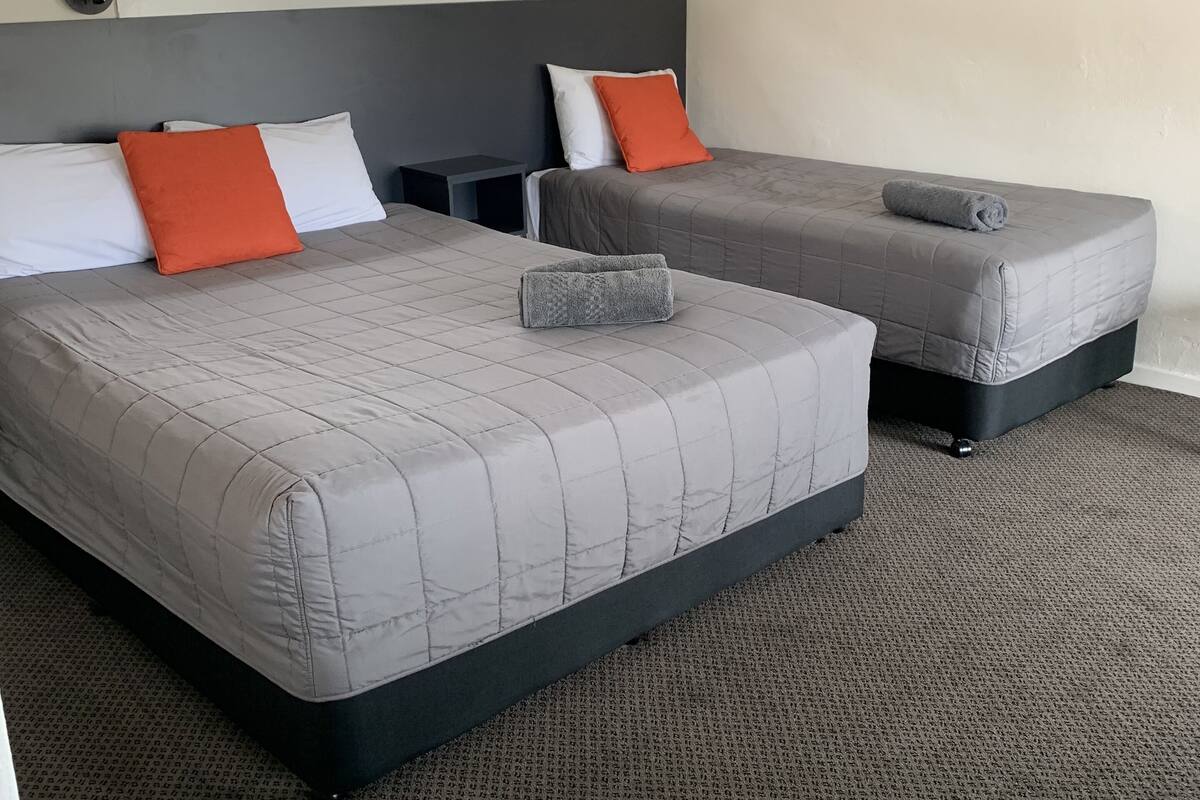 A hotel room with two beds, a window, and a carpeted floor.