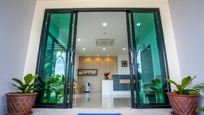 A hotel entrance with a 'WELCOME' mat, glass doors, potted plants, and a reception area in the background. - Wanarom Residence Hotel (Krabi)