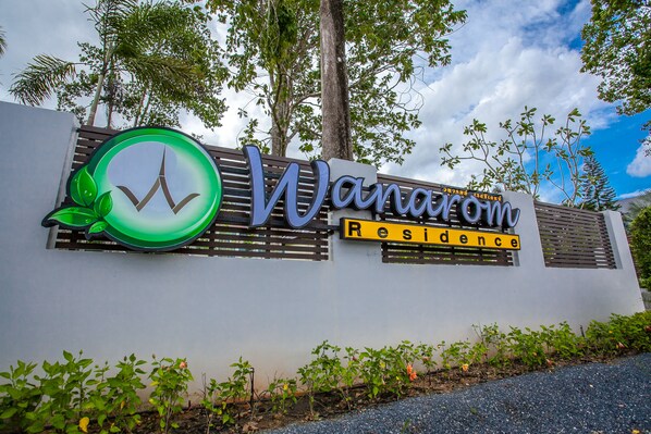 A sign for "Wanavcom Residence" with a green logo and a modern design. - Wanarom Residence Hotel (Krabi)
