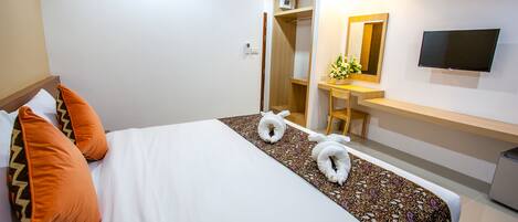 A hotel room with a bed, a desk, a TV, and a wardrobe.