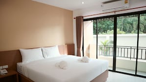 A hotel room with a large bed, a bedside telephone, and a view of a balcony with greenery. - Wanarom Residence Hotel (Krabi)