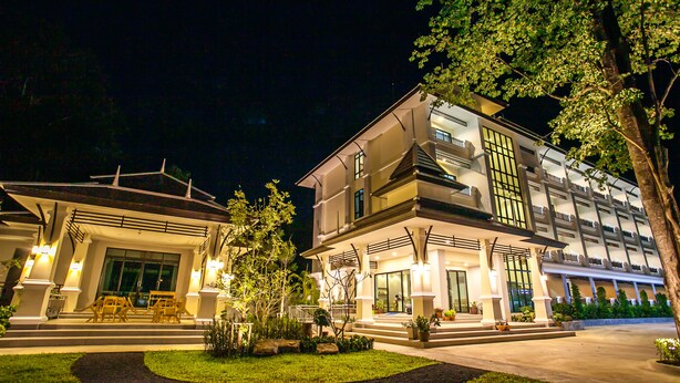A modern hotel with a well-lit entrance, outdoor seating, and a landscaped garden. - Wanarom Residence Hotel (Krabi)