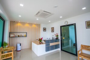 A reception area with a reception desk, a clock, framed pictures, a potted plant, and a bench. - Wanarom Residence Hotel (Krabi)