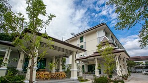 A two-story building with a covered porch, outdoor seating, and a well-maintained garden. - Wanarom Residence Hotel (Krabi)