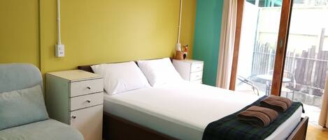 A bedroom with a bed, bedside tables, a chair, and a window with a view of the outside.