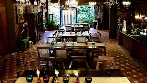 Un ristorante con diversi tavoli e sedie, un'area bar e vista su spazi verdi esterni.