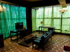 Una sala de estar con televisor, sofá y mesa.
