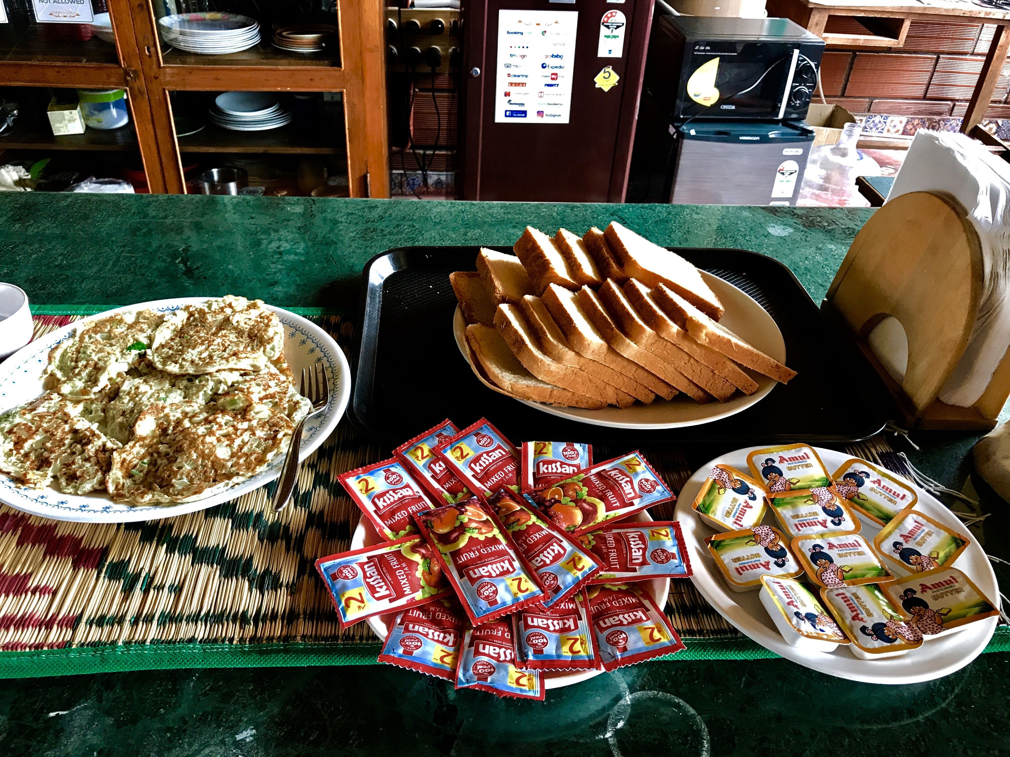 A buffet table with various food items including a bowl of salad, sliced bread, and packets of snacks.