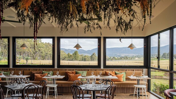 A restaurant with large windows offering a view of the countryside. Tables are set with chairs and wine glasses. - Harkham Lodge (Pokolbin)