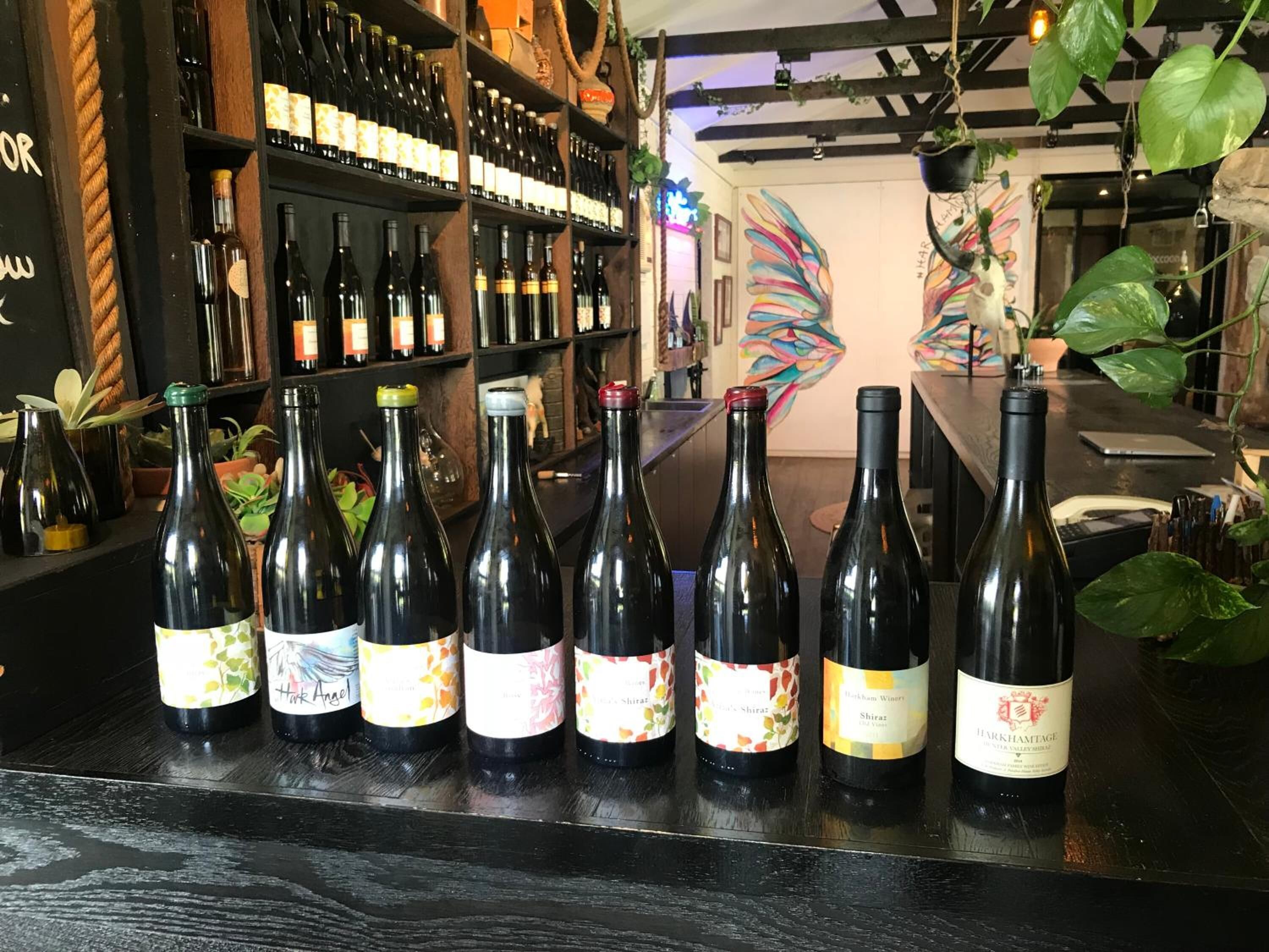 A bar with wine bottles and shelves of bottles in the background.