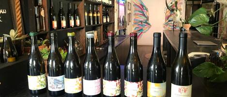 A bar with wine bottles and shelves of bottles in the background.