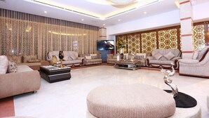 A spacious living room with a modern chandelier, comfortable seating, and a flat-screen TV. - Marino Royal Hotel (Dhaka)