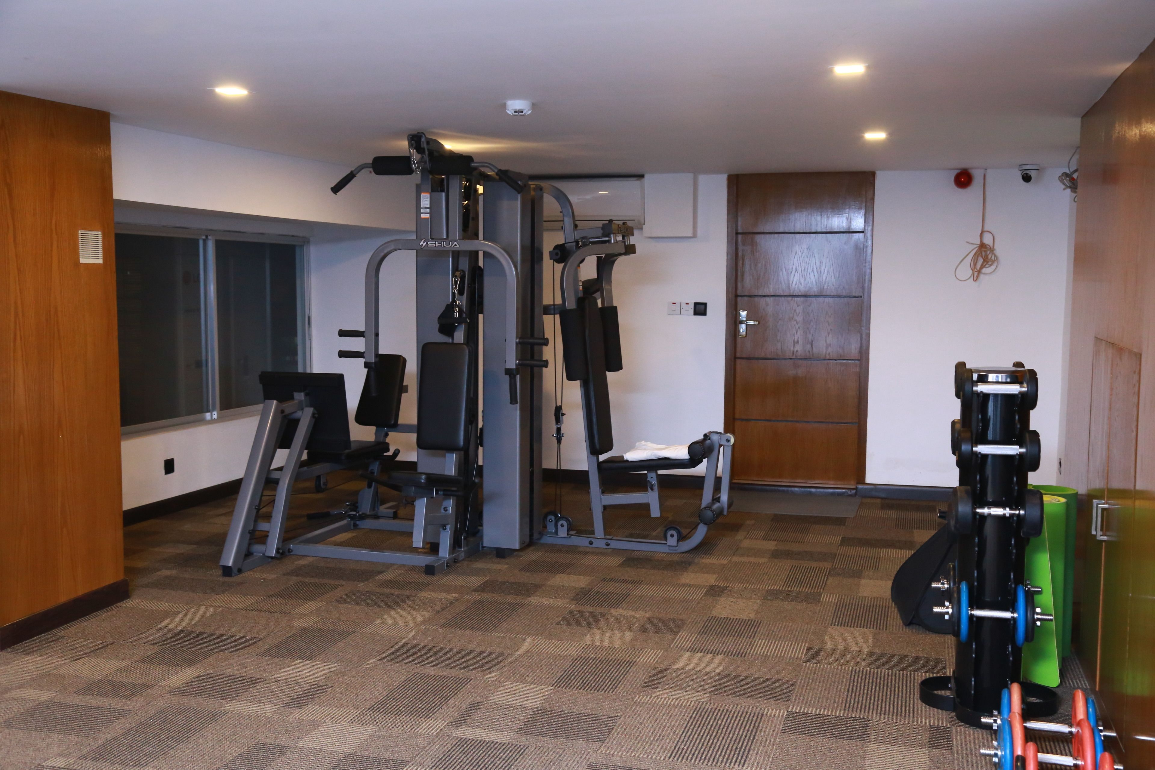 A gym with exercise equipment, a window, and a door.