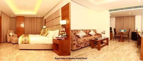 A hotel room with a large bed, a sofa, a small table, and a desk.