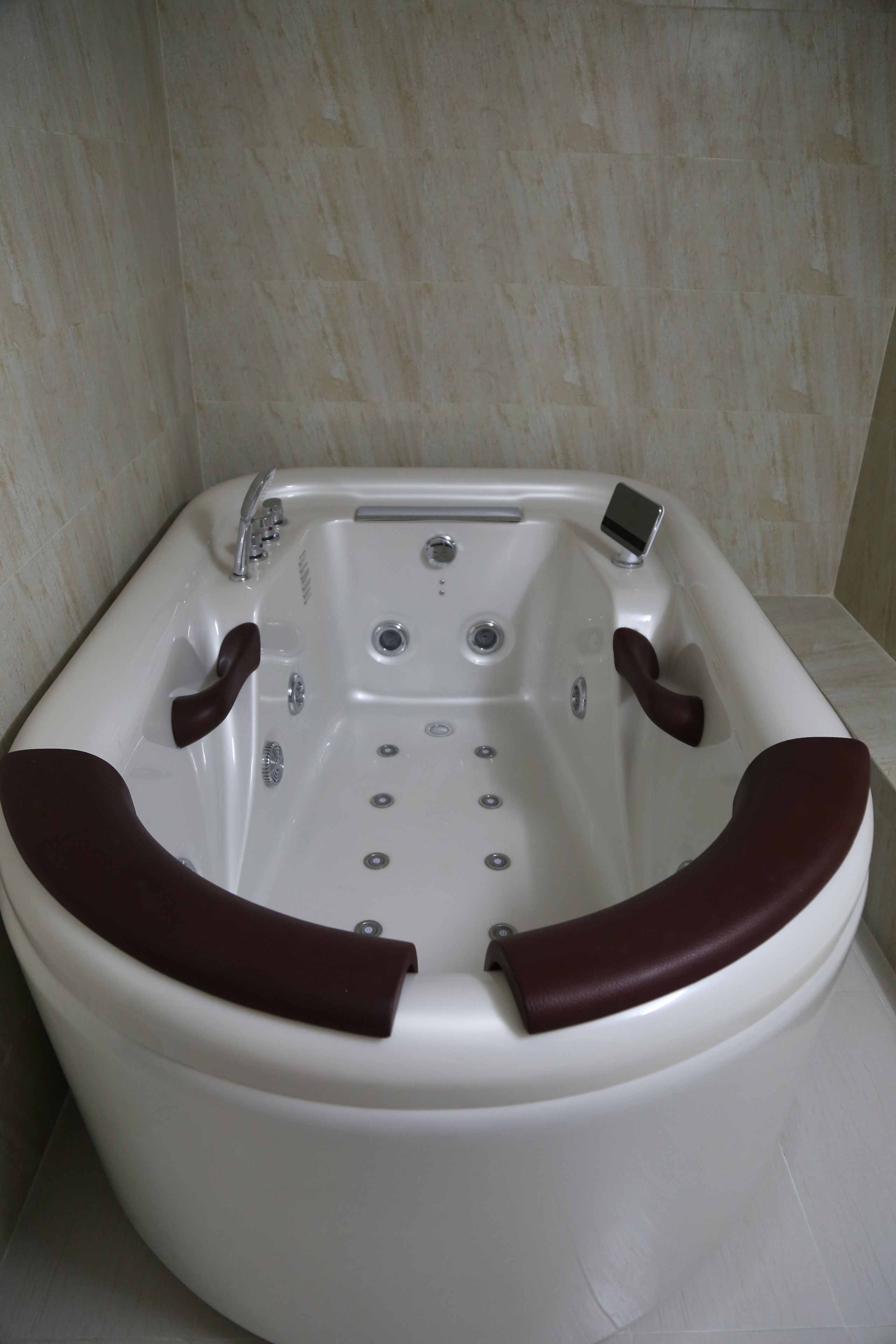 Une baignoire blanche dotée d’un panneau de commande, de deux robinets et d’une douchette.