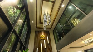 A modern hotel lobby with a vertical wooden panel design, a central hanging light fixture, and large windows. - Feliz Urban Hotel (Phnom Penh)