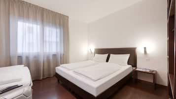Una camera d'albergo con un letto grande, un comodino, una sedia e una finestra con tende.