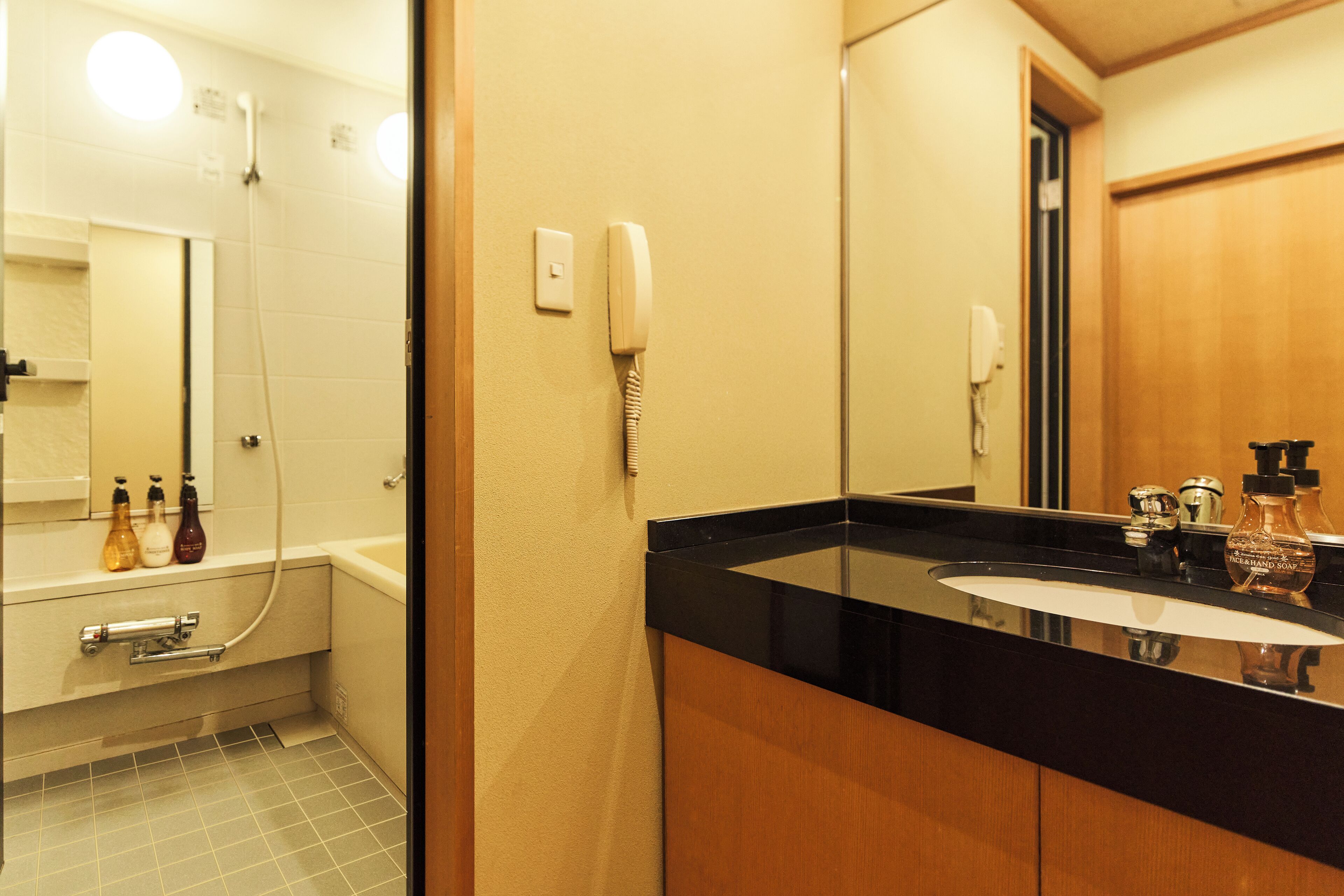 Een badkamer met een zwart wastafel, een spiegel, een telefoon en een douche.
