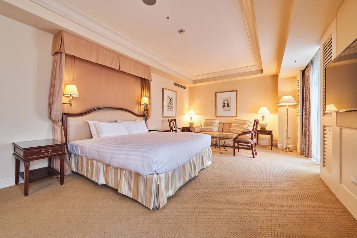 A hotel room with a large bed, bedside tables, a desk, and a chair.