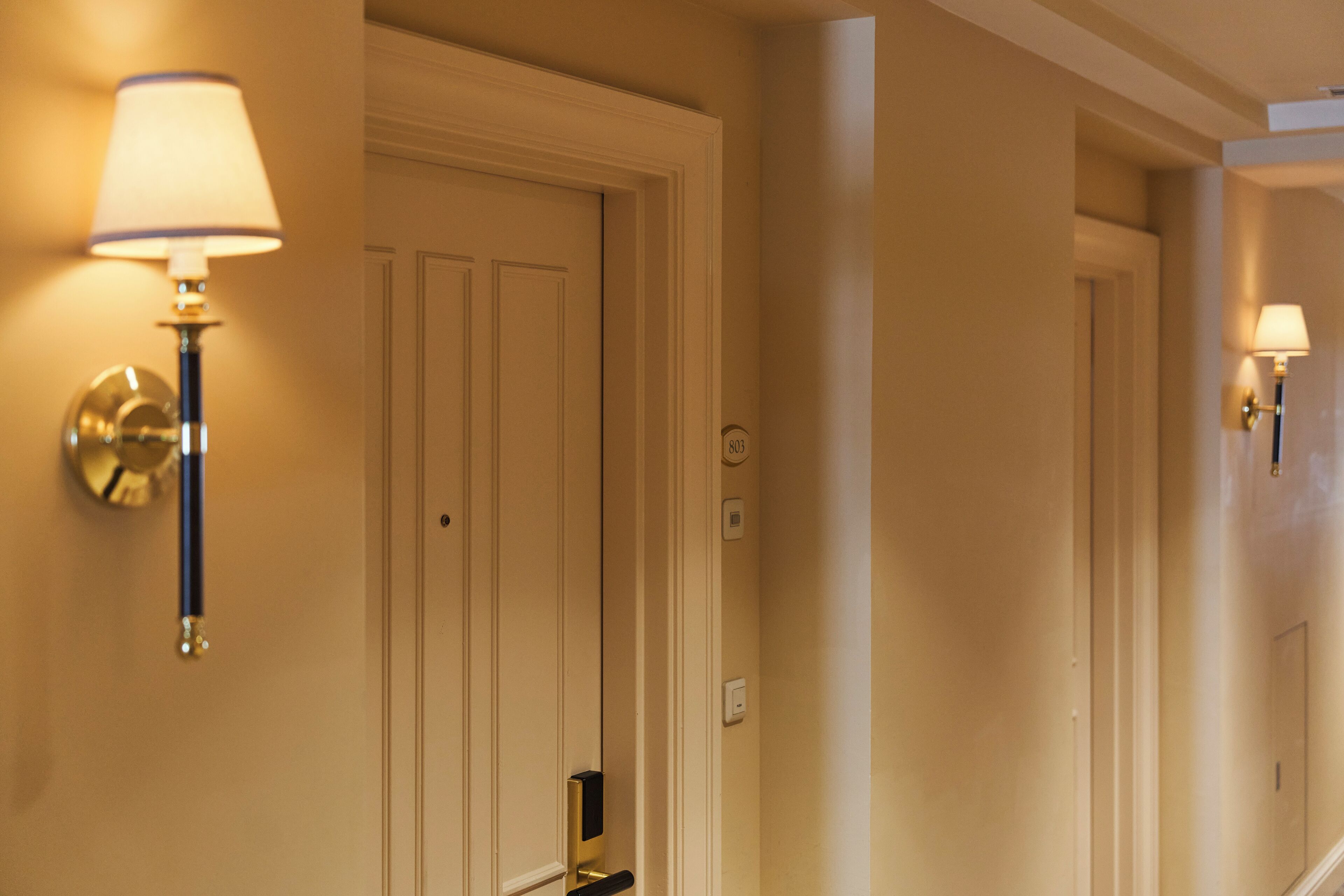 A hallway with two doors, each with a wall-mounted lamp.