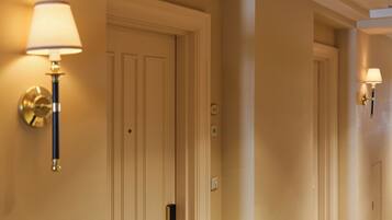 A hallway with two doors, each with a wall-mounted lamp.