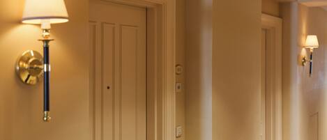 A hallway with two doors, each with a wall-mounted lamp.