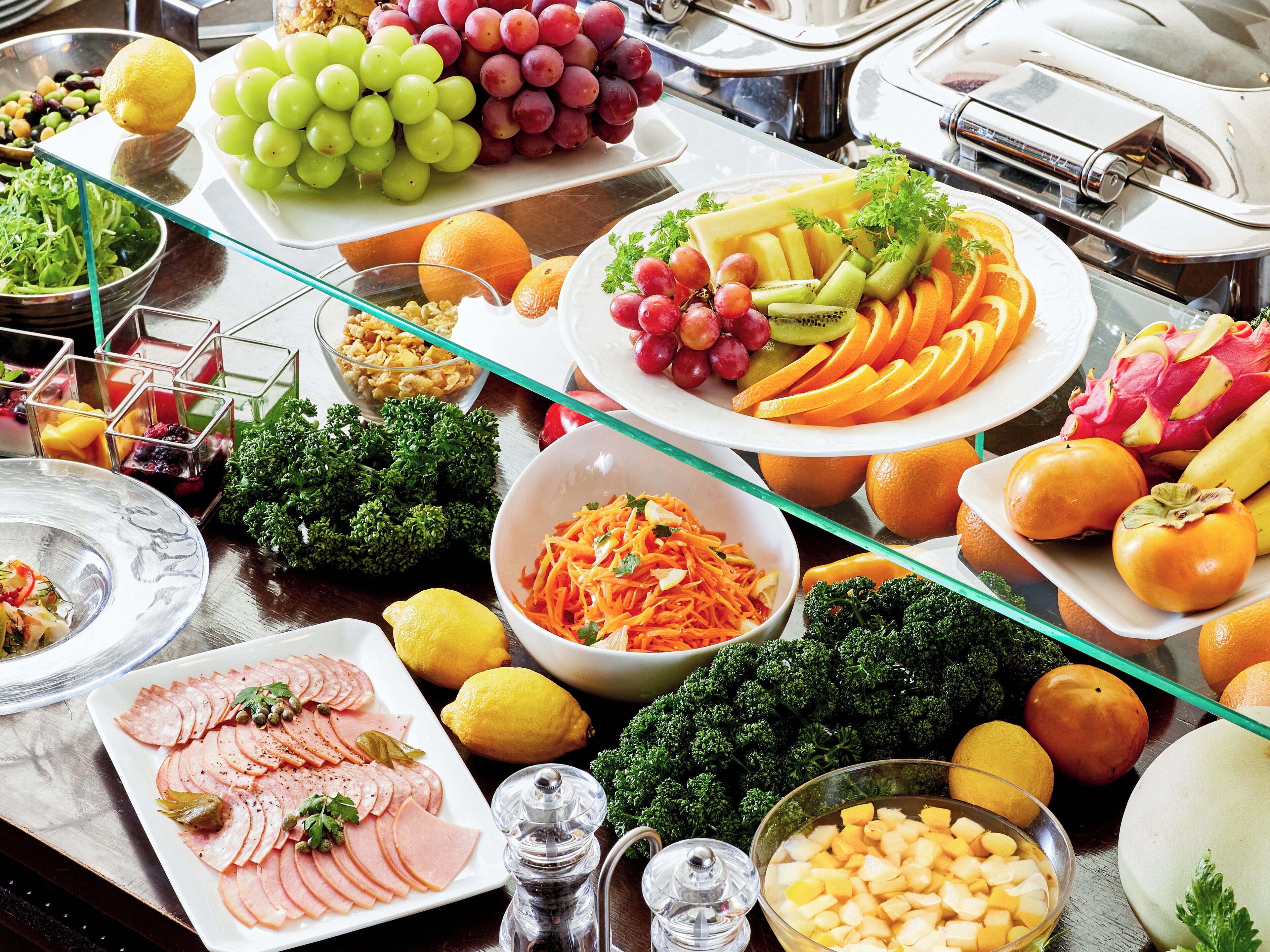 A buffet table with various food items including fruits, vegetables, and salads.