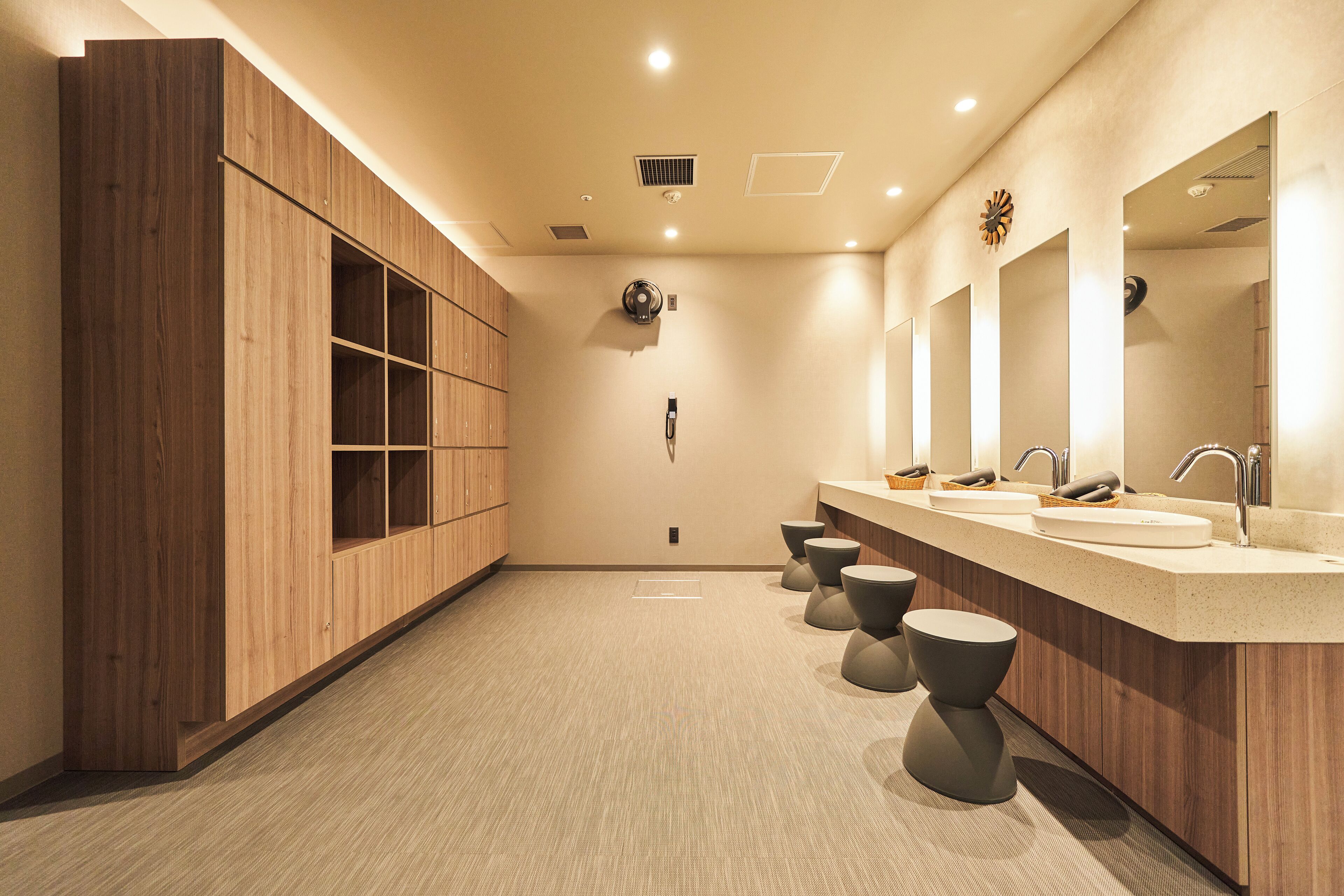 Un baño moderno con armarios de madera, un espejo grande y tres lavamanos.