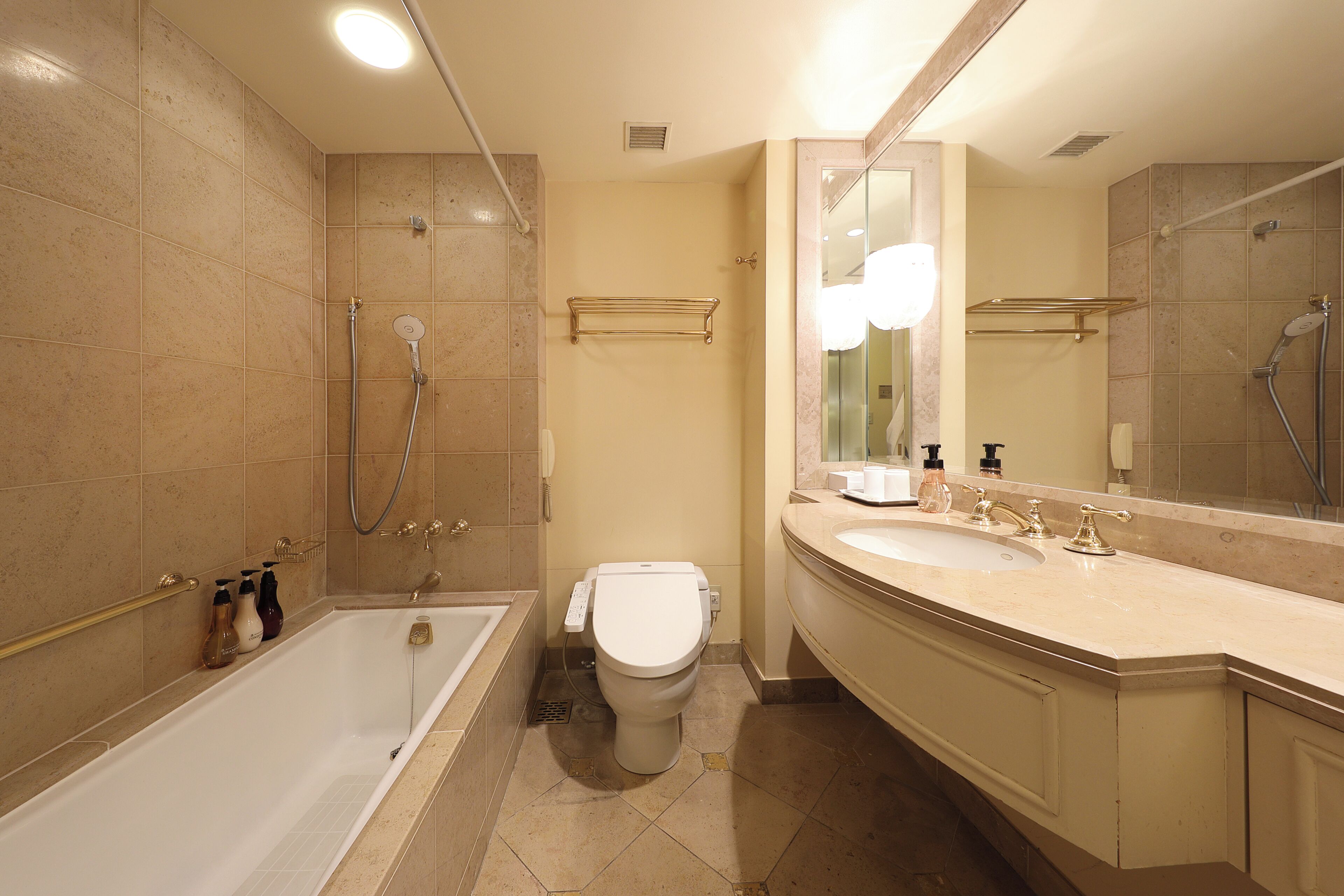 A modern bathroom with a bathtub, toilet, and vanity with a large mirror.