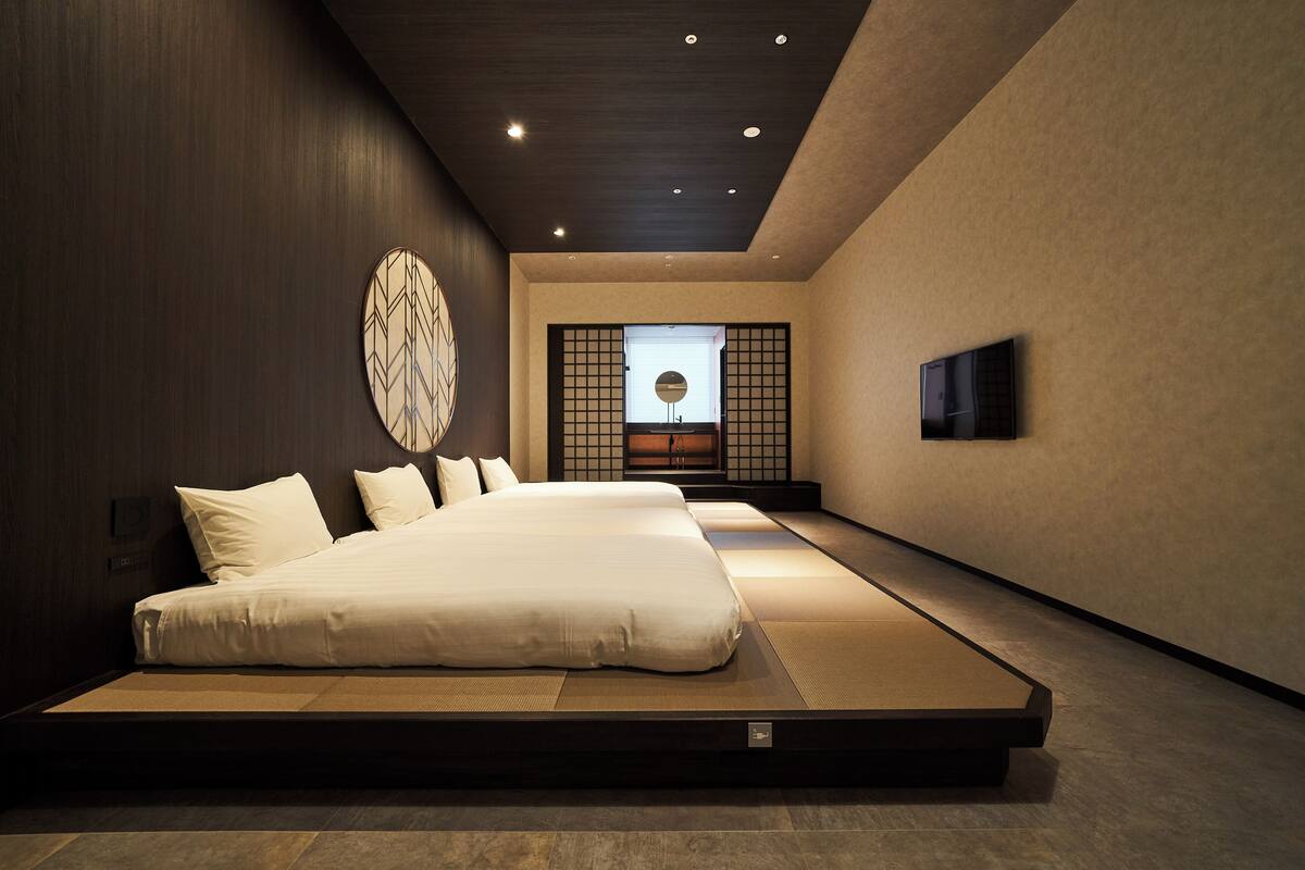 A modern hotel room with a large bed, a TV, and a traditional Japanese sliding door.