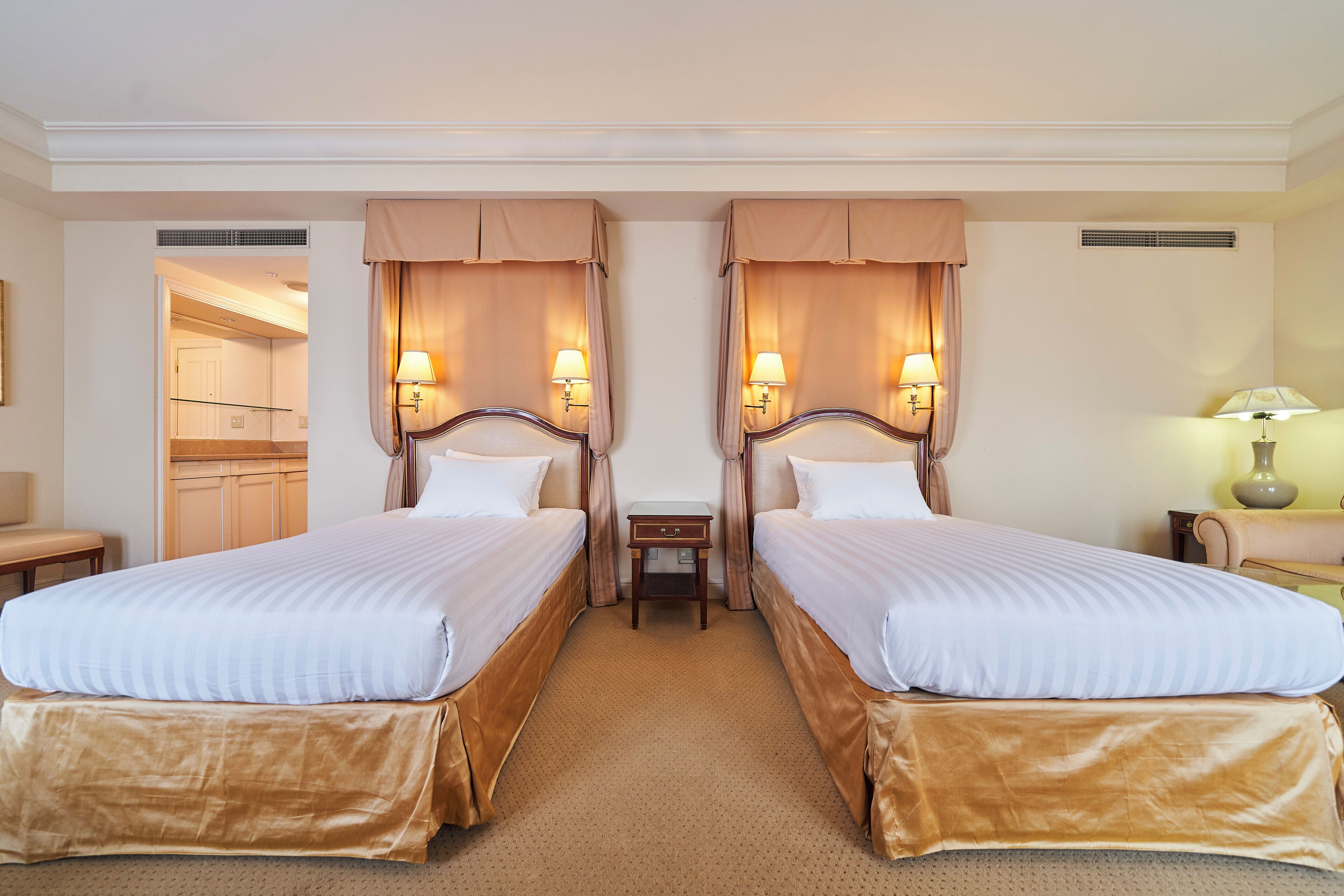 Ein Hotelzimmer mit zwei Betten, einem kleinen Tisch und einer Lampe.