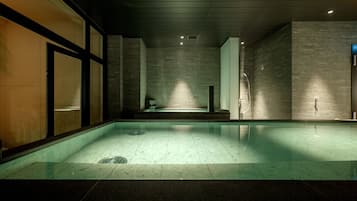 Ein moderner Poolbereich im Innenbereich mit Glasboden, gefliesten Wänden und minimalistischem Design.