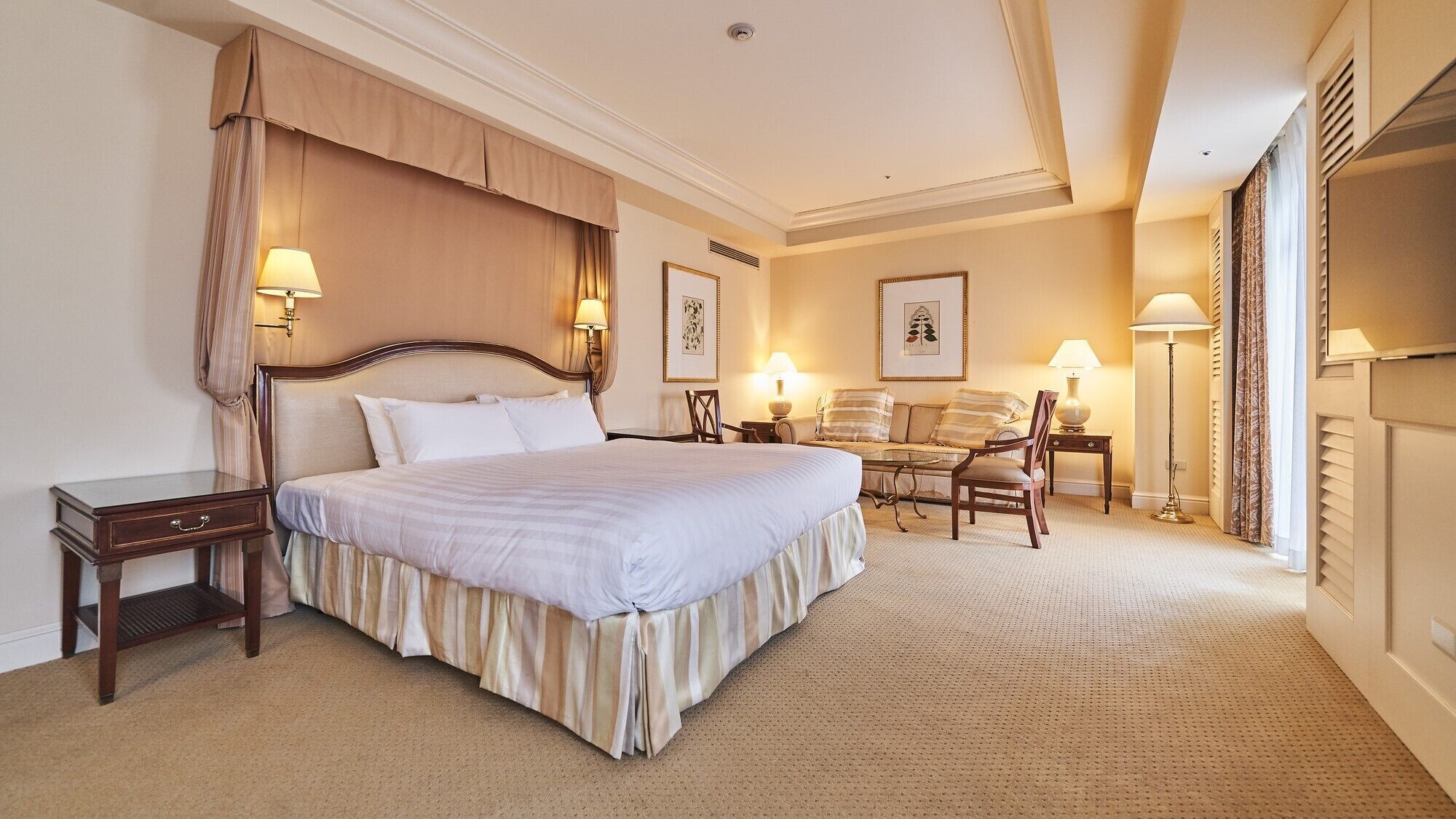 Una habitación de hotel con una cama grande, mesitas de noche, una silla, un escritorio y una lámpara.