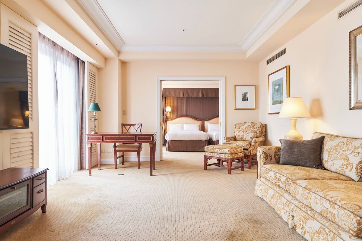 A hotel room with a bed, a sofa, a desk, and a TV.