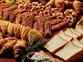 Variedad de pasteles y pan, incluyendo croissants, gofres y una selección de pan cortado.