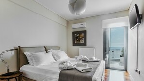 Ein Schlafzimmer mit Bett, Schreibtisch, Lampe, Fernseher und Blick ins Freie.