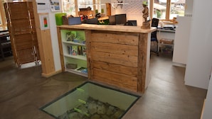 A reception area with a wooden counter, a glass display case with rocks, and a green shelf with various items. - Bergsteiger-Hotel Grüner Hut (Bad Hindelang)