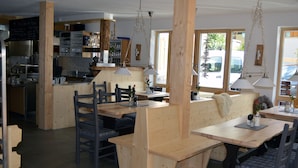 A restaurant with wooden furniture, a bar area, and large windows. - Bergsteiger-Hotel Grüner Hut (Bad Hindelang)