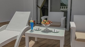 A white wicker lounge chair and table set up on a balcony with a fruit bowl and a blue drink on the table. - The Green Oasis Otel & Spa (Yalova)