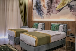 A hotel room with two beds, a wooden headboard, a green and white patterned rug, and a large abstract painting on the wall. - The Green Oasis Otel & Spa (Yalova)