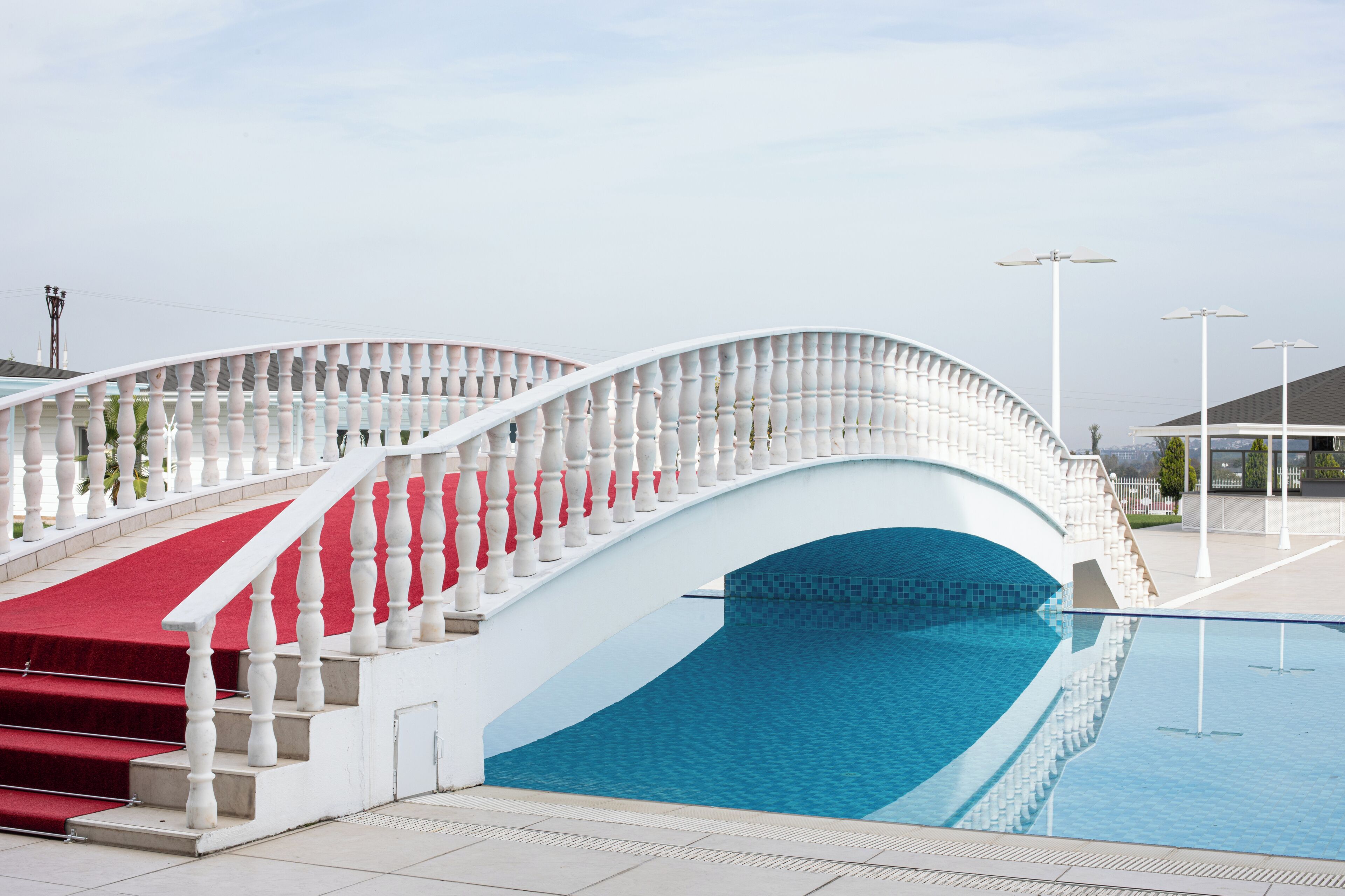A white bridge with balustrades leading to a pool area.